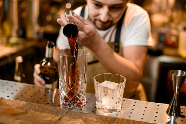 istock Bartender pouring a brown alcoholic drink from the jigger to a mixing glass 1188989051