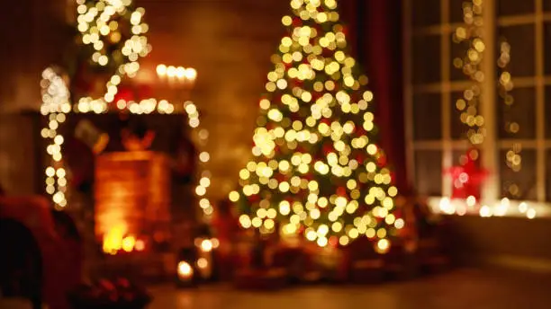 blurred interior christmas. magic glowing tree, fireplace, gifts in  dark at night