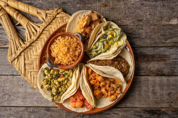 Traditional mexican stew tacos also called "guisados" with rice on wooden background