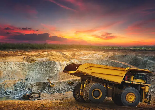 Yellow dump truck loading minerals copper, silver, gold, and other  at mining quarry.