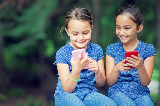 istock Two sisters are playing with their mobile phones 1189003589