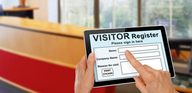 Visitor completing a sign in register form on computer tablet stock photo