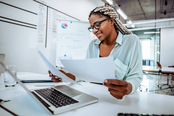istock Smiling business woman reads documents, works in a bright office. 1189010349