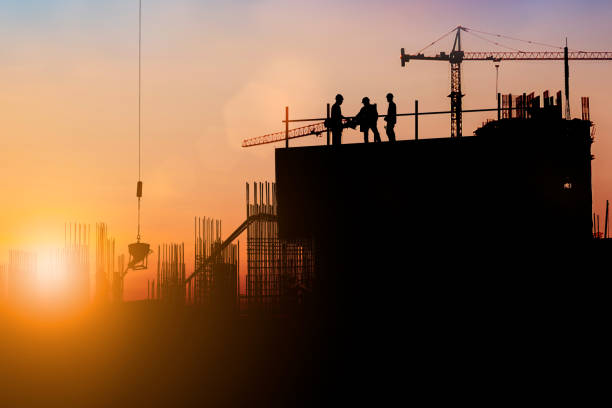 光フェアと業界背景の背景をぼかした写真を現場で働くエンジニアと建設チームのシルエット。一緒に複数の参照画像から作成します。 - construction site crane construction silhouette ストックフォトと画像