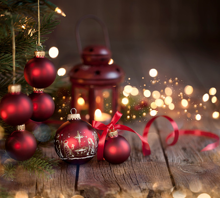Christmas tree with red baubles & nativity Christmas ornaments on an old wood background with defocused lights
