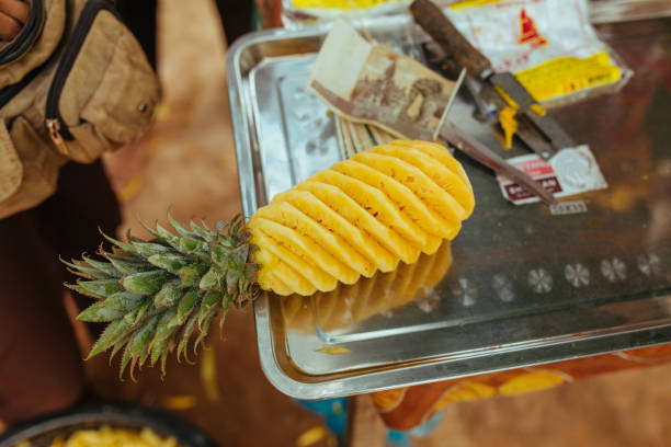Extreme macro close-up of sliced pineapple wedges with hands slicing wedges in the background.