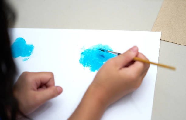 istock kid hand brush and drawing paper for art work,back view 1189046170