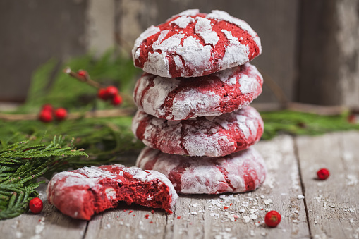 Stack of red velvet crinkle Christmas cookies with garland on a vintage wooden background