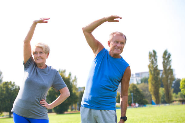 istock Senior couple doing stretching exercise in park against sky 1189049775