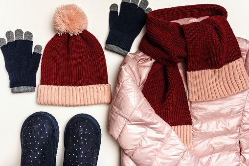Top view on a set of warm clothing on a white background. Jacket, gloves, hat, scarf, shoes.