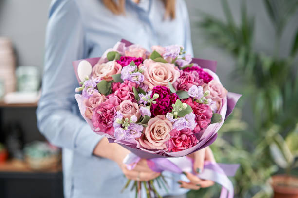 tienda de flores europea. hermoso ramo de flores mezcladas en manos de las mujeres. el trabajo de la floristería en una floristería. entrega flor fresca cortada. - multi colored flower red flower head fotografías e imágenes de stock