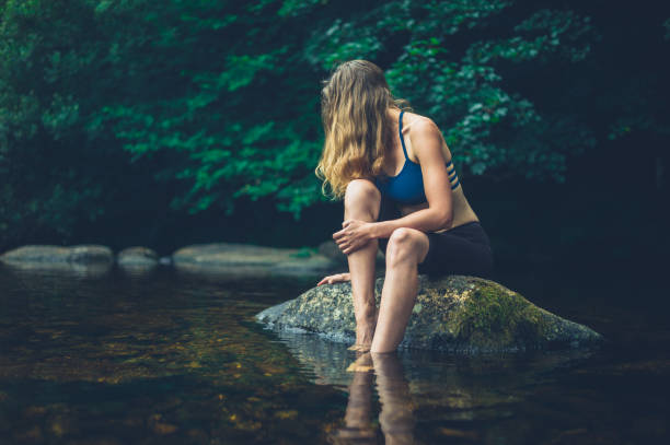 istock Woman relaxing on rock in river 1189056158