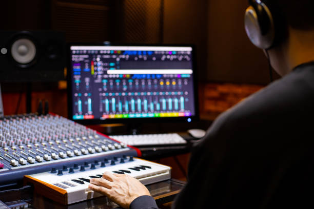 ホームレコーディングスタジオでミディキーボードとコンピュータ上の曲を手配するアジアの男性音楽プロデューサーの背中。音楽制作コンセプト - lyricist ストックフォトと画像