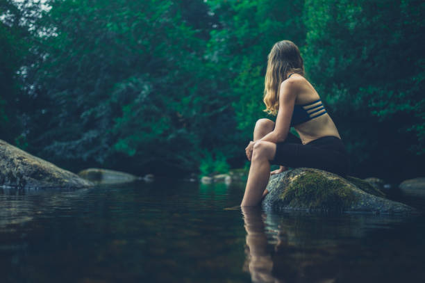 istock Woman relaxing on rock in river 1189062108