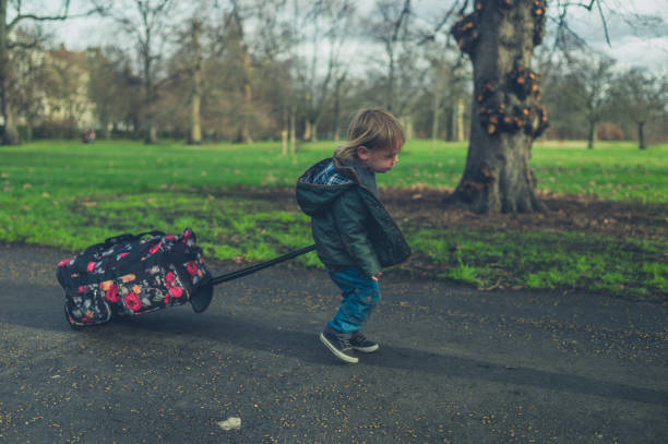 istock Little toddler pulling suitcase in the park 1189065522