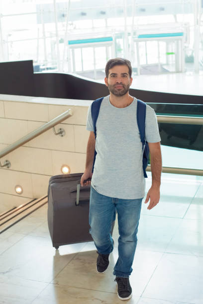 istock Smiling young man walking with luggage 1189066802