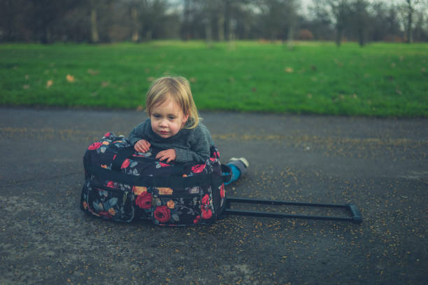 istock Little toddler resting on suitcase in park 1189067733