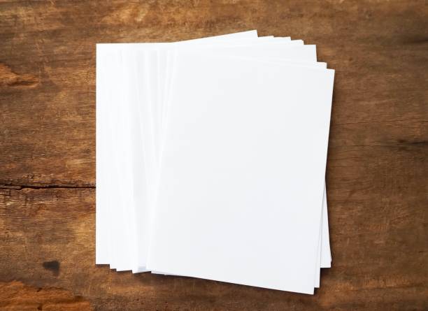 istock Several sheets of white paper on a wood background. 1189068954