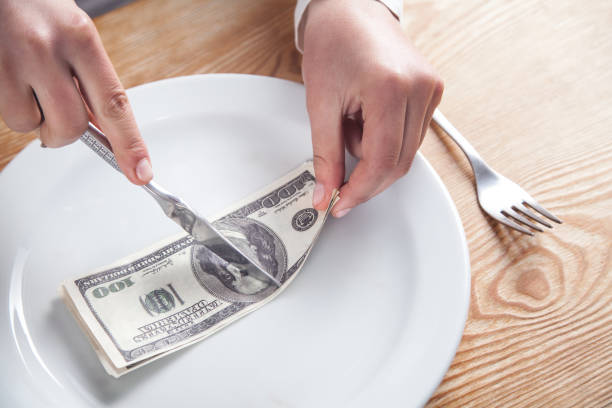 istock Hands cutting dollar banknote on the plate. 1189070238