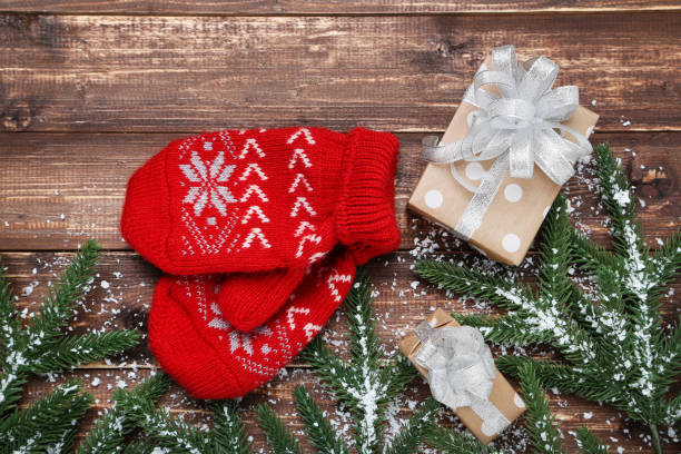 istock Knitted mittens with fir tree branches and gift box on wooden table 1189072211