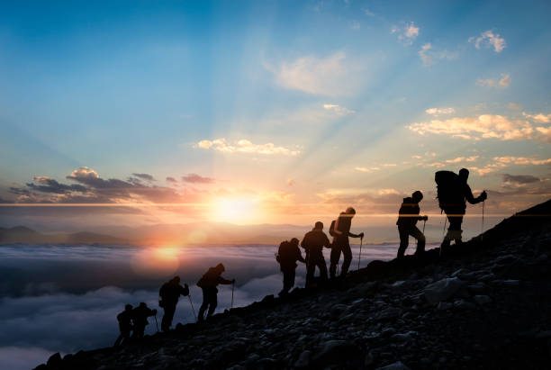 sagome di escursionisti al tramonto - inerpicarsi foto e immagini stock