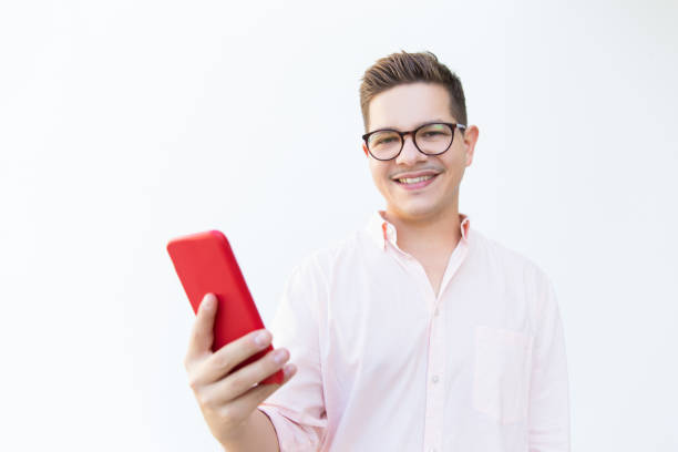 istock Happy content guy in eyeglasses holding red mobile phone 1189074146