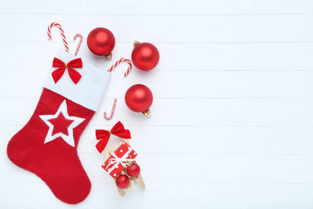 istock Red stocking with christmas ornaments on white wooden table 1189074686