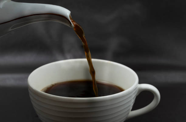 Close up pouring the black coffee from pot into cup