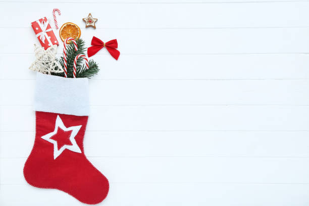 istock Red stocking with christmas ornaments on white wooden table 1189077521