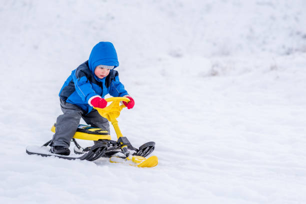 istock little child riding a snow scooter in winter 1189077627