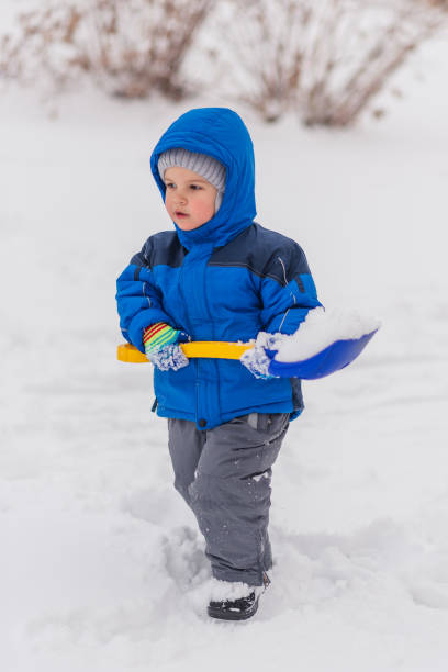 istock A little boy is digging snow with a shovel in the winter. 1189078819