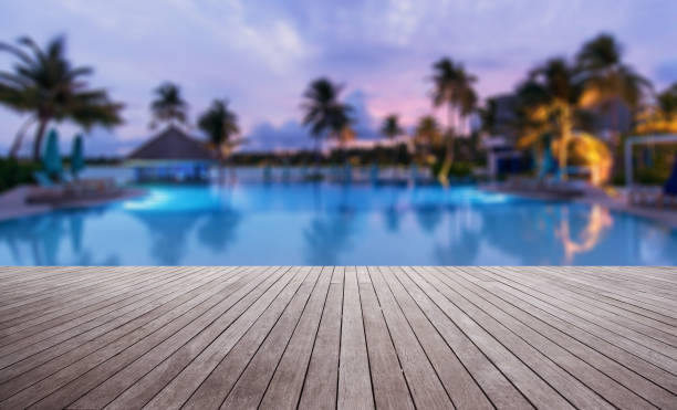 terraza de madera junto a la piscina del complejo tropical al atardecer - swimming pool resort swimming pool poolside sea fotografías e imágenes de stock