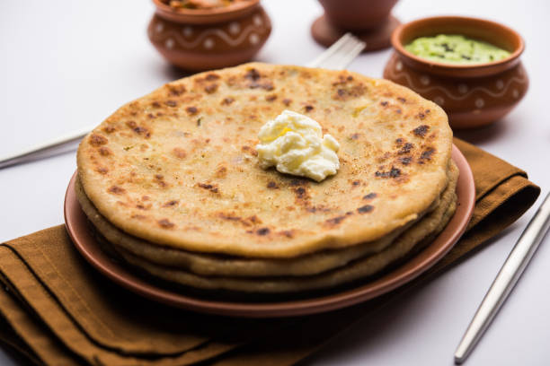 Aloo Paratha with lassi / Indian Potato stuffed Flatbread with butter on top. Served with fresh sweet Lassi, chutney and pickle . selective focus stock photo