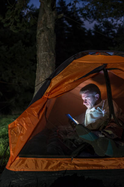 istock Man watching his smartphone in a tent. 1189084489