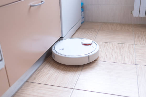 istock Robotic vacuum cleaner on the floor cleaning the kitchen. Smart cleaning technology. 1189085212