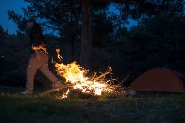 istock Man lights a fire in the fireplace in nature 1189085279