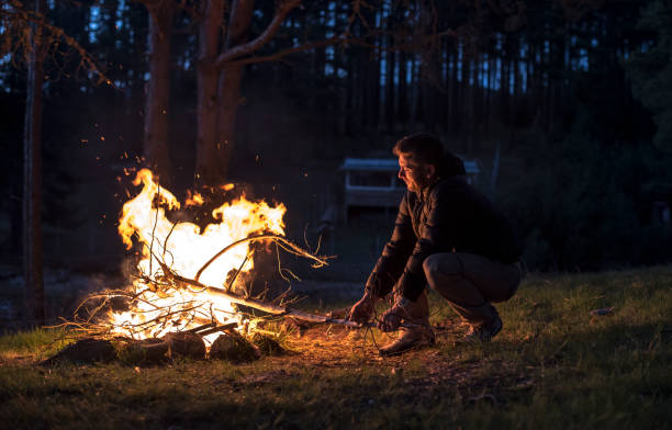 istock Man lights a fire in the fireplace in nature 1189085571