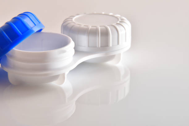 istock Contact lens case open reflected on white glass table 1189086271