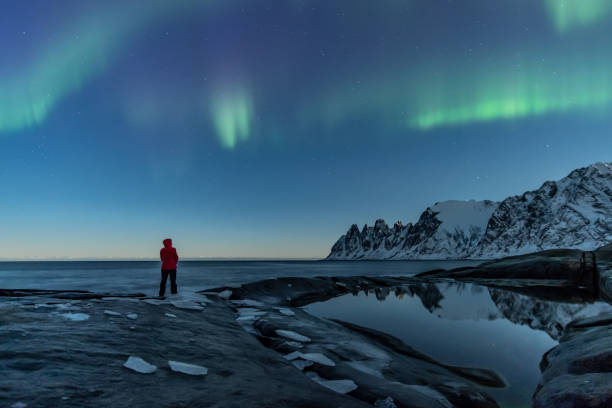 istock Woman watching the northern lights, Aurora Borealis, Devil Teeth mountains in the background, Tungeneset, Senja, Norway 1189086708