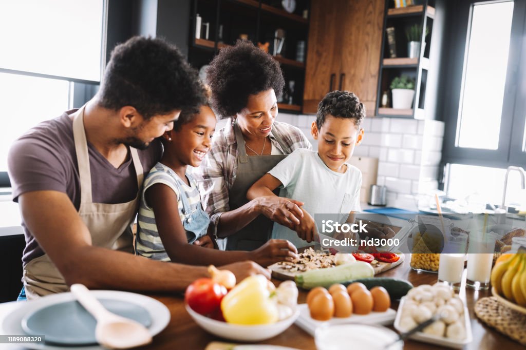 Happy african american family preparing healthy food together in kitchen Happy african american family preparing healthy organic food together in kitchen Family Stock Photo