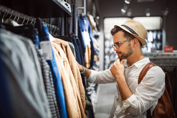 homme bel faisant des achats pour de nouveaux vêtements dans le magasin - mens clothes photos et images de collection