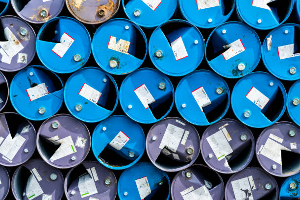 old chemical barrels. blue and purple oil drum. steel oil tank. toxic waste warehouse. hazard chemical barrel with warning label. industrial waste in metal drum. hazard waste storage in factory. - oil storage tank storage compartment fuel and power generation imagens e fotografias de stock