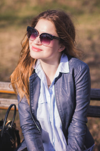 istock Woman sitting on bench and relaxing on sunny day 1189093898