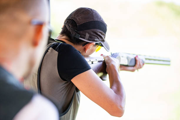 Adult Woman Shooting With a Shotgun Outdoors - Stock Photo Adult Woman Shooting With a Shotgun Outdoors. trap shooting stock pictures, royalty-free photos & images