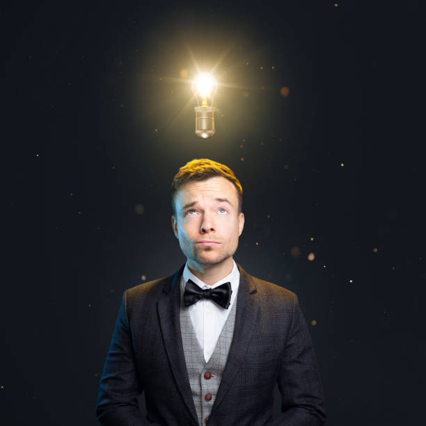 Man with a light bulb above the head A well-dressed man is looking up towards a light bulb above his head. man with a light bulb over his head stock pictures, royalty-free photos & images