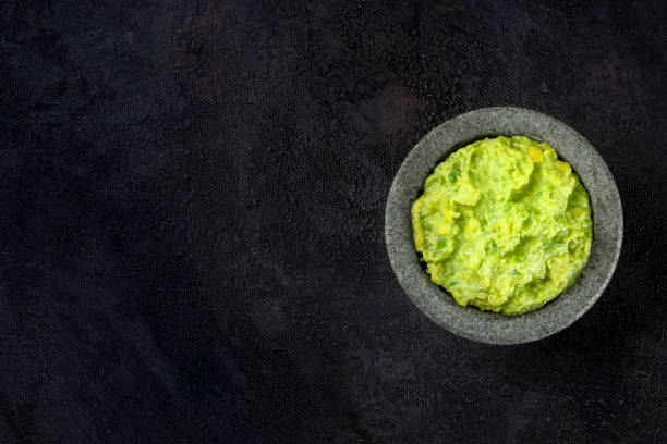 istock Guacamole avocado dip in a molcajete, typical Mexican stone mortar, top shot on a dark background with copy space 1189096613
