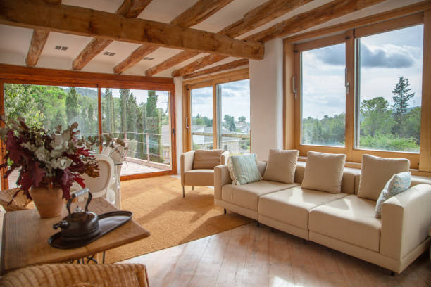 Upper living room view on to garden, pool and courtyard of Spanish farmhouse, Barcelona Elegant farmhouse second living area with sofas and easy chairs and patio doors on to upper terrace roof beam stock pictures, royalty-free photos & images