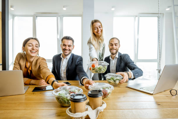 Office employees with healthy takeaway food indoors Portrait of a group of office workers taking business lunches in the office. Concept of healthy takeaway food on the work lunch stock pictures, royalty-free photos & images