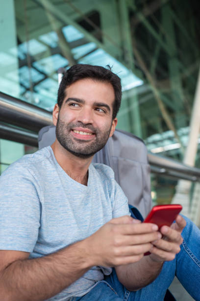 istock Cheerful handsome man holding smartphone at airport 1189101512