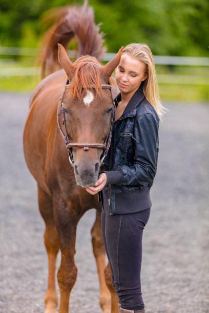 istock Young woman with her arabian horse standing at a riding course 1189102964